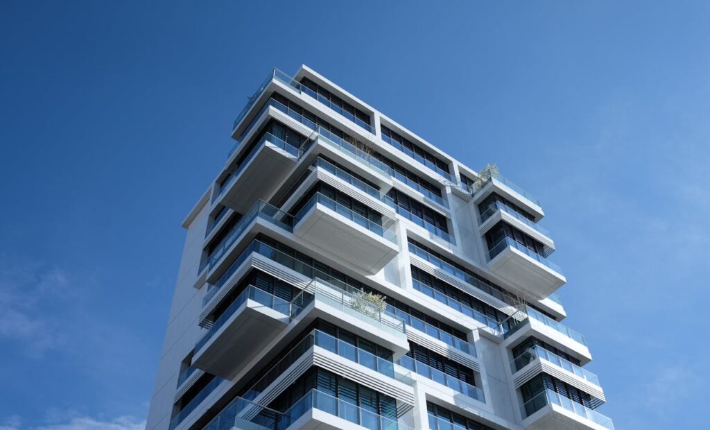 Mastering the First Impression: Your intriguing post title goes here Striking low-angle shot of a modern condominium with unique balcony design and clear blue sky.