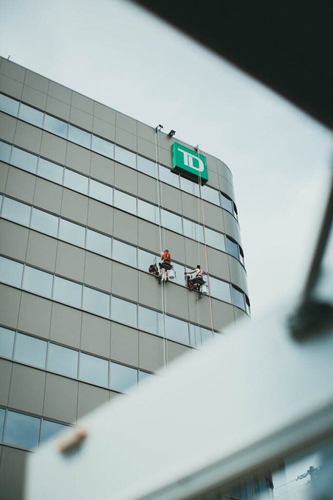 Crafting Captivating Headlines: Your awesome post title goes here Two professional window cleaners working on a skyscraper with a corporate logo.